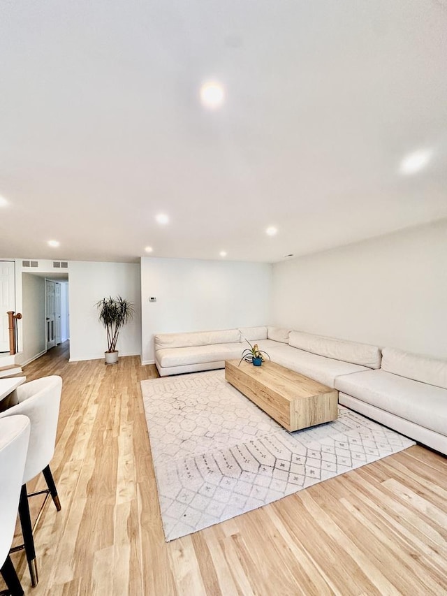 living area with light wood-type flooring, visible vents, and recessed lighting