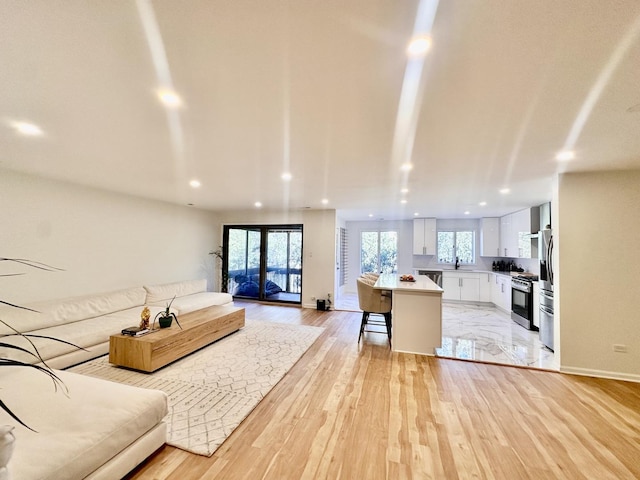 living room with recessed lighting, light wood-style flooring, and baseboards