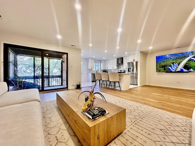 living room featuring light wood-style flooring, baseboards, and recessed lighting