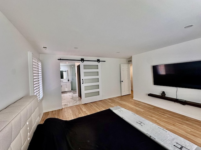 unfurnished living room with baseboards, visible vents, light wood finished floors, and a barn door