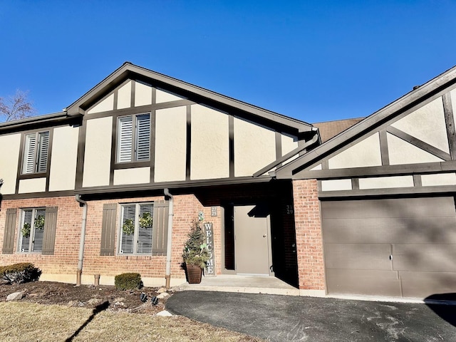 exterior space featuring brick siding, driveway, an attached garage, and stucco siding