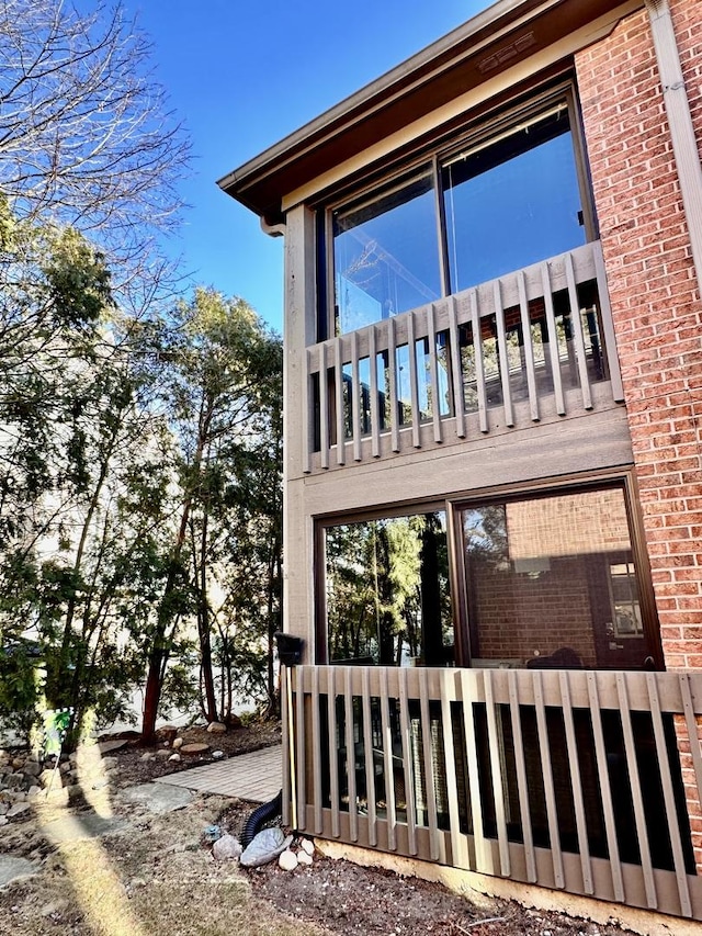 view of side of home with brick siding and a balcony