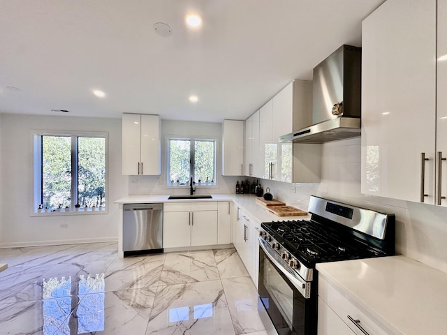 kitchen with marble finish floor, wall chimney exhaust hood, stainless steel appliances, and a sink