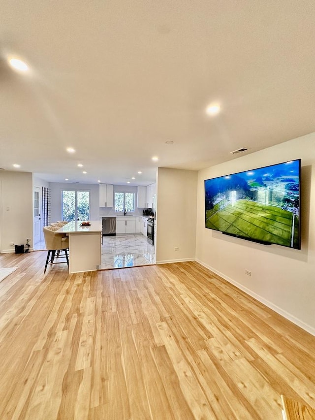 unfurnished living room featuring baseboards, light wood finished floors, visible vents, and recessed lighting