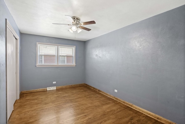 unfurnished bedroom with ceiling fan, wood finished floors, visible vents, baseboards, and a closet