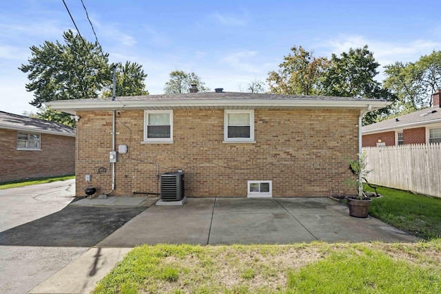 back of house featuring central AC unit, brick siding, a patio area, and fence