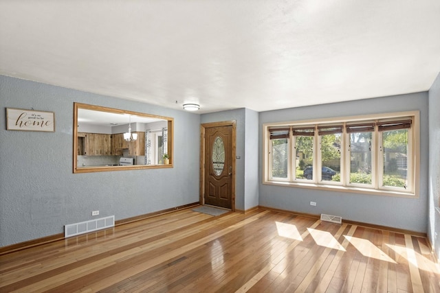 entryway with an inviting chandelier, baseboards, visible vents, and hardwood / wood-style floors