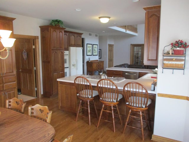 8032 Abbey Rd, Tinley Park, IL 60477 - kitchen featuring a peninsula, white refrigerator with ice dispenser, light wood-type flooring, a breakfast bar area, and brown cabinets
