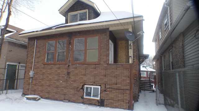 view of snowy exterior with brick siding