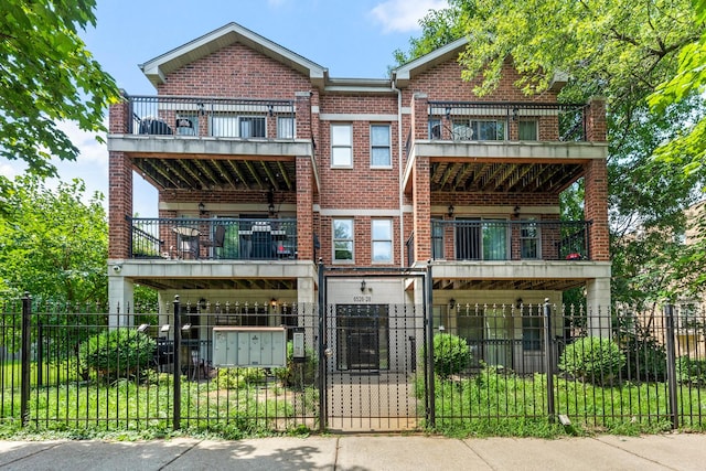 view of front of house featuring a balcony, a fenced front yard, a gate, and brick siding