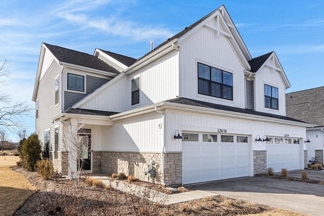 view of front of property featuring an attached garage, stone siding, and driveway