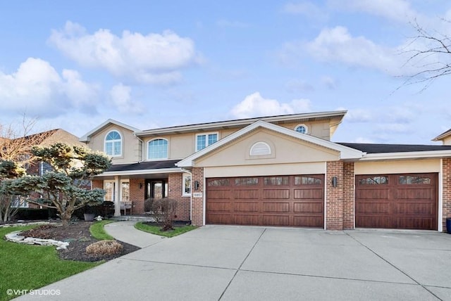 view of front of home with a garage, driveway, brick siding, and stucco siding