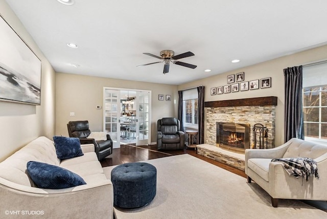 living room with recessed lighting, a healthy amount of sunlight, a stone fireplace, and wood finished floors