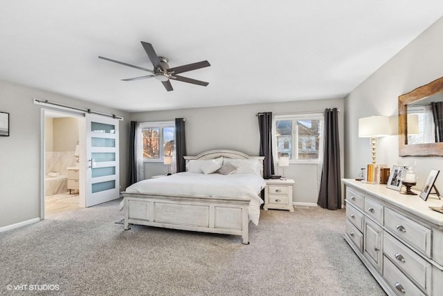 bedroom featuring light carpet, connected bathroom, baseboards, and a barn door