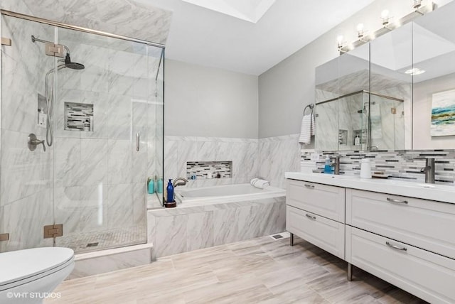 full bathroom with a skylight, a marble finish shower, toilet, vanity, and a bath