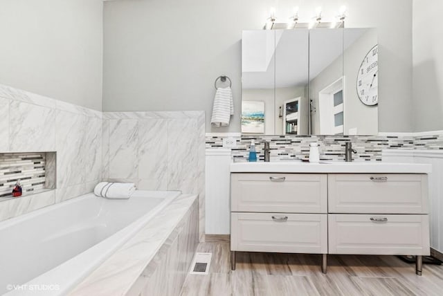 full bath with wood finished floors, visible vents, vanity, backsplash, and a bath