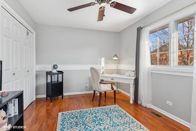 office featuring ceiling fan, wood finished floors, visible vents, and baseboards