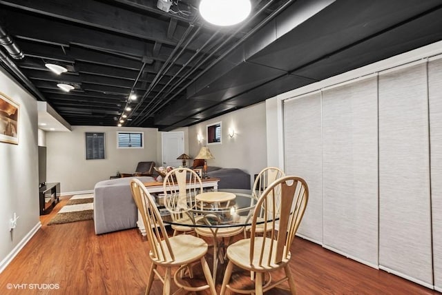 dining space with track lighting, baseboards, and wood finished floors