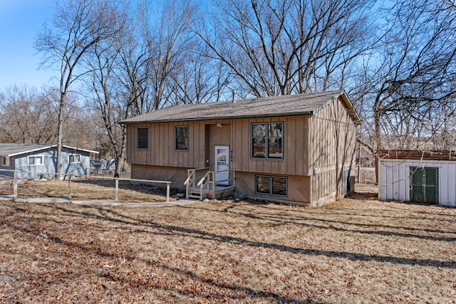 raised ranch featuring entry steps, a storage unit, an outdoor structure, and fence