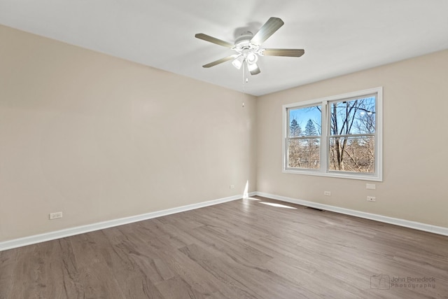 empty room with visible vents, dark wood finished floors, baseboards, and ceiling fan