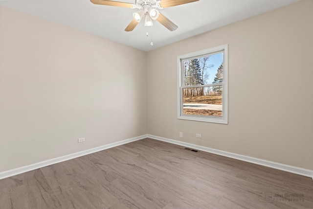 empty room featuring visible vents, baseboards, and wood finished floors