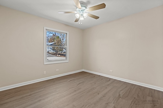 empty room featuring wood finished floors, a ceiling fan, and baseboards