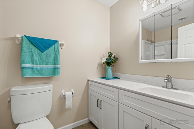 bathroom with baseboards, visible vents, vanity, and toilet