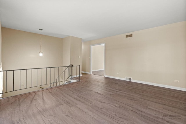 unfurnished room with baseboards, visible vents, and wood finished floors