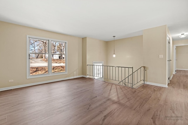 spare room featuring visible vents, baseboards, and wood finished floors