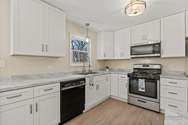 kitchen featuring light countertops, appliances with stainless steel finishes, white cabinetry, a sink, and light wood-type flooring