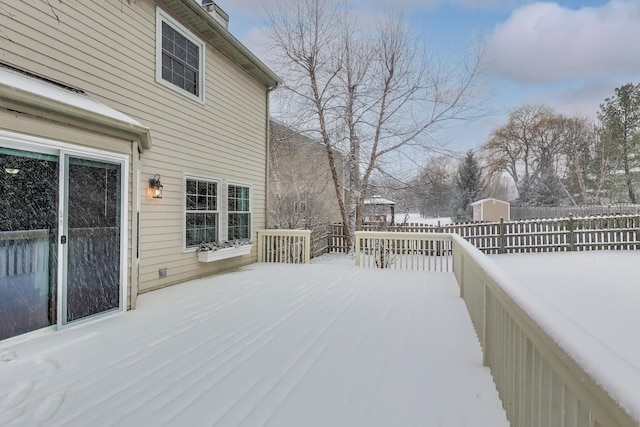 snow covered deck featuring fence and an outbuilding