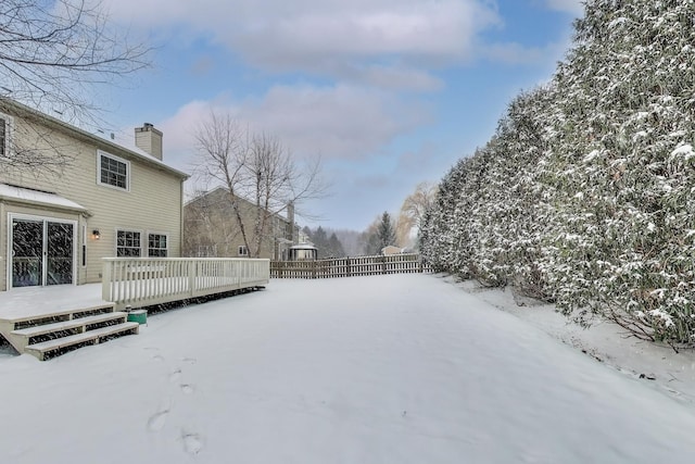 snowy yard with fence and a deck