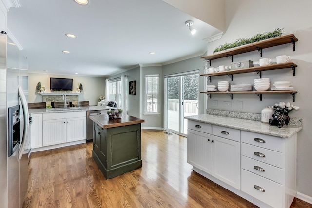 kitchen featuring stainless steel appliances, wooden counters, light wood-style floors, ornamental molding, and a sink