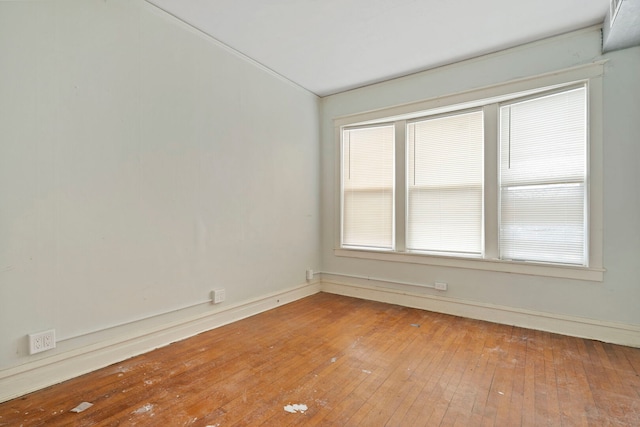 spare room featuring wood-type flooring and baseboards