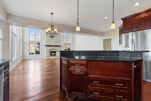 kitchen featuring appliances with stainless steel finishes, reddish brown cabinets, dark wood-style flooring, and a kitchen island