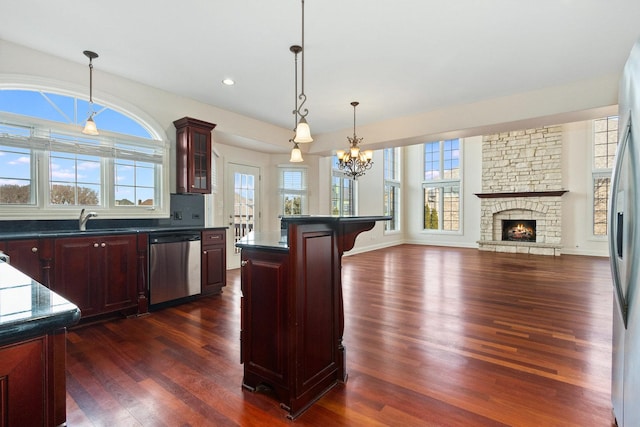 kitchen with a breakfast bar area, a sink, dark brown cabinets, stainless steel dishwasher, and dark countertops