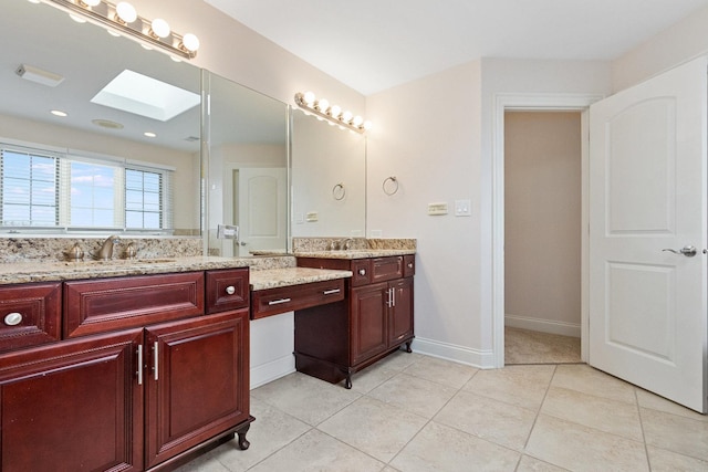 full bathroom with two vanities, a skylight, a sink, and tile patterned floors