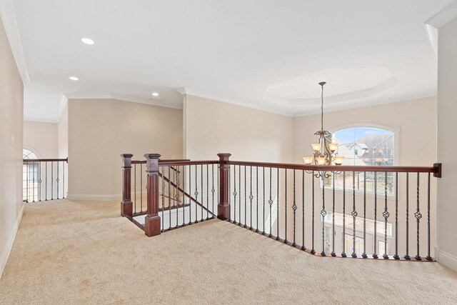 corridor with baseboards, an inviting chandelier, carpet, crown molding, and an upstairs landing