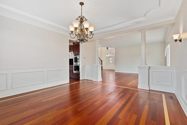 spare room featuring a notable chandelier, dark wood-style flooring, and ornate columns