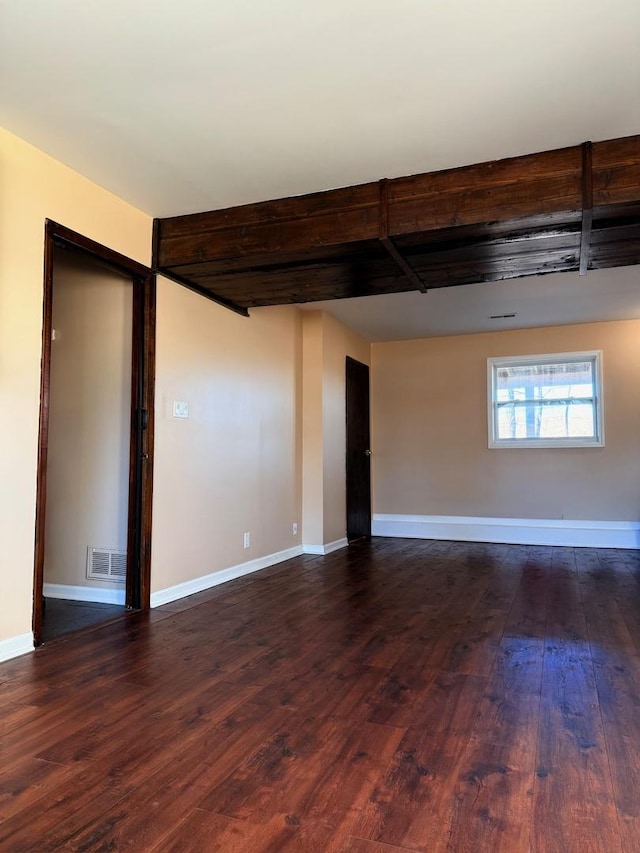 spare room with visible vents, baseboards, and dark wood finished floors