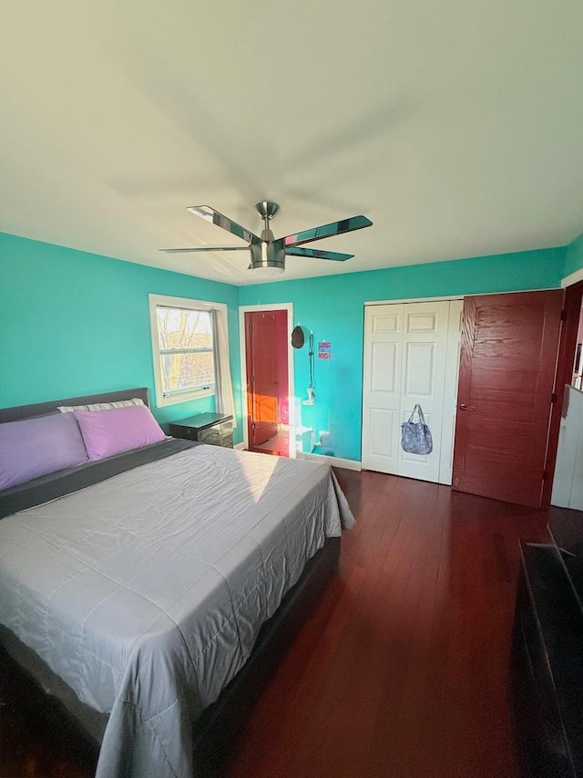 bedroom with ceiling fan, dark wood-type flooring, a closet, and baseboards