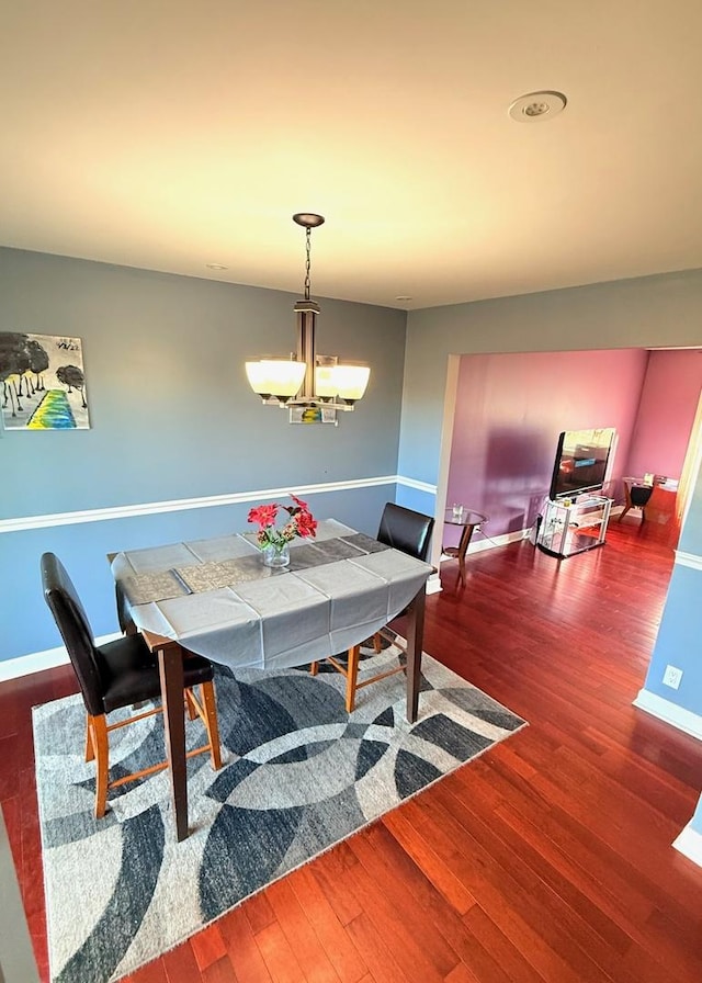 dining room with a chandelier, wood finished floors, and baseboards