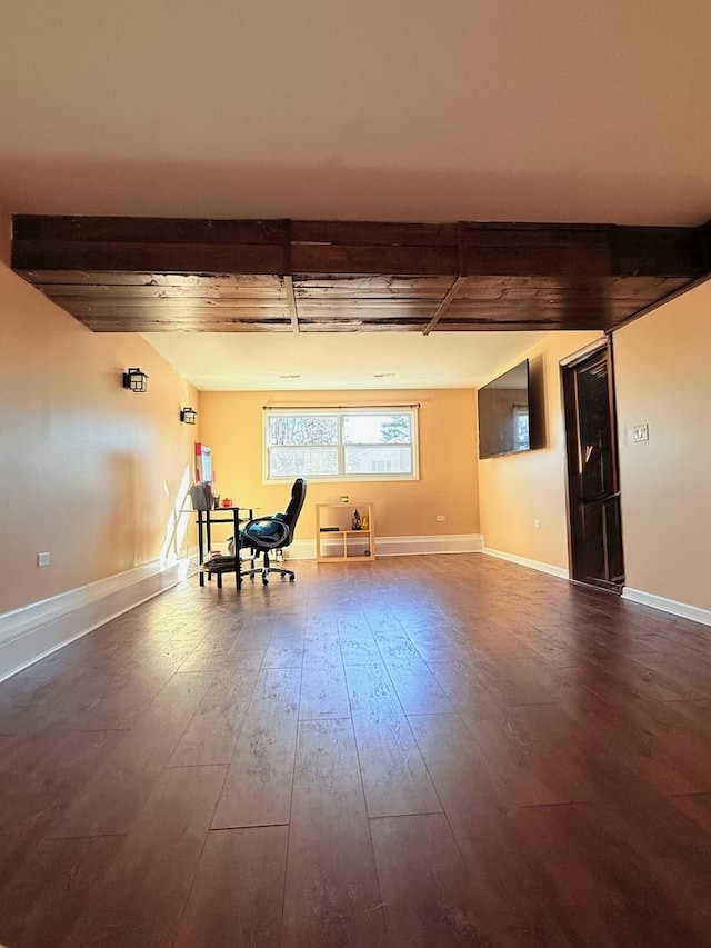 unfurnished room with wood finished floors, beam ceiling, and baseboards