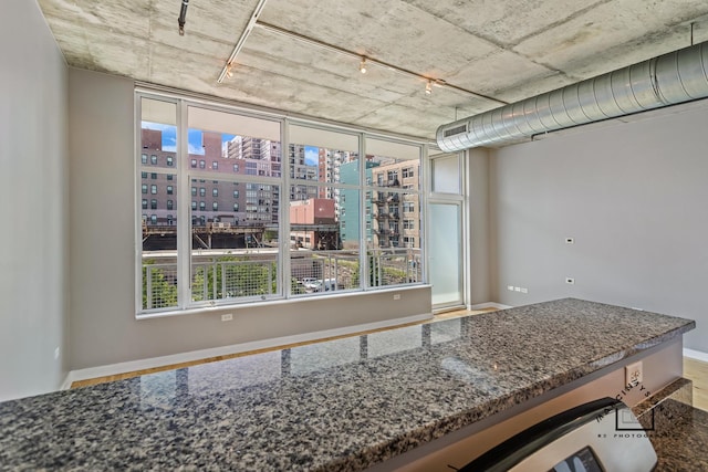 kitchen featuring baseboards, dark stone counters, and a city view