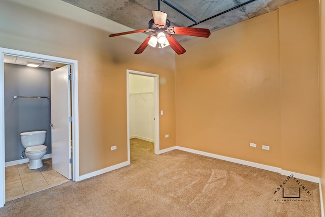 unfurnished bedroom featuring carpet, baseboards, a walk in closet, and connected bathroom