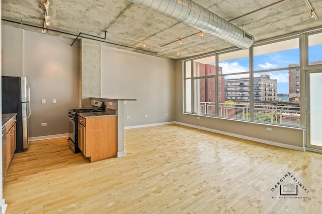 kitchen featuring baseboards, appliances with stainless steel finishes, brown cabinets, a view of city, and light wood finished floors