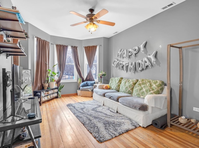 living area featuring hardwood / wood-style flooring, visible vents, and a ceiling fan