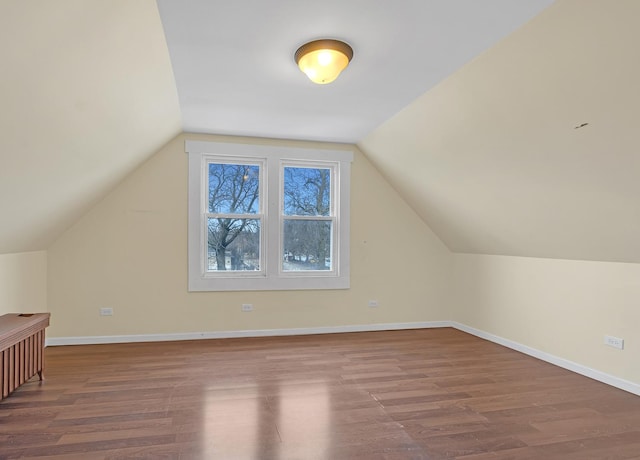 additional living space with baseboards, vaulted ceiling, and wood finished floors