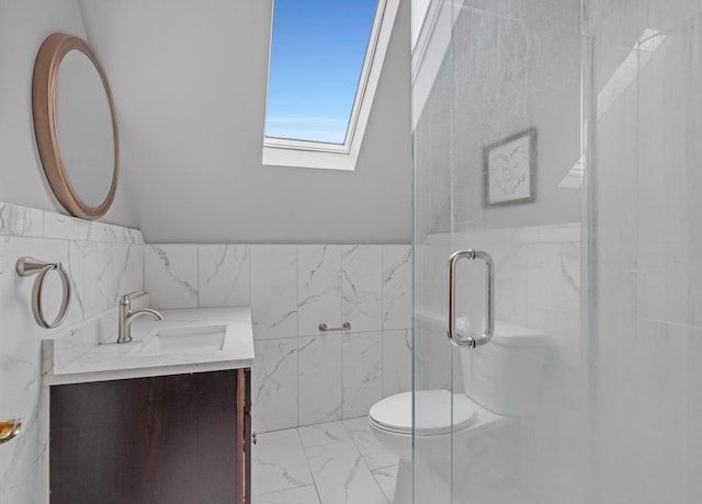 bathroom featuring a skylight, toilet, marble finish floor, vanity, and a shower stall