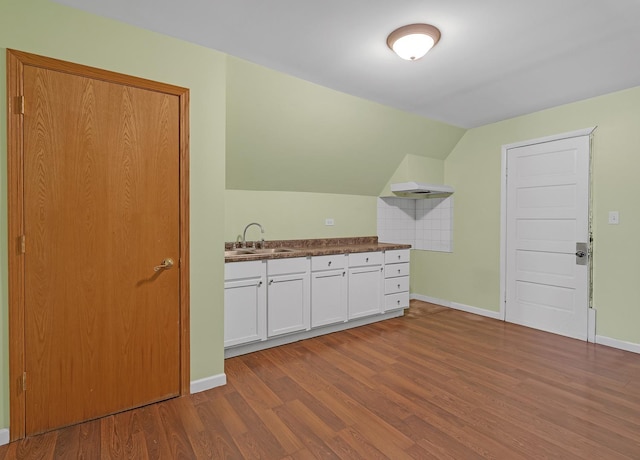 interior space with lofted ceiling, baseboards, a sink, and wood finished floors